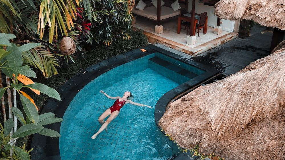 donna in costume a mollo nella piscina di un hotel tropicale